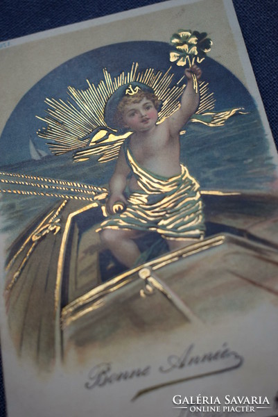 New Year greeting card pressed with antique gold - little sailor on a ship, 4-leaf clover, golden sunset