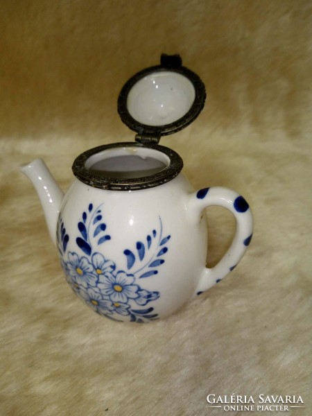 Decorative metal jewelry holder in the shape of a coffee pourer with a blue pattern.