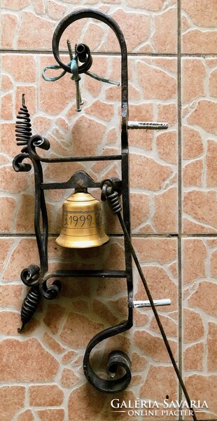 A copper bell made by an artisan, for sale mounted on a wrought iron block.