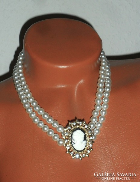 A beautiful, shiny double row of pearls, with a pendant decorated with a cameo and rhinestones.