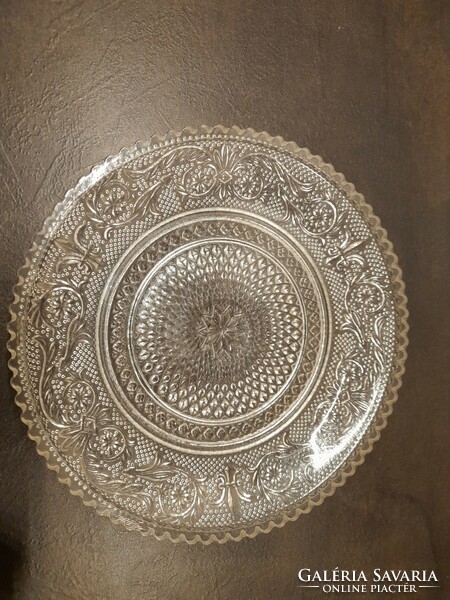 A very old glass cake plate with relief pattern and jagged edges