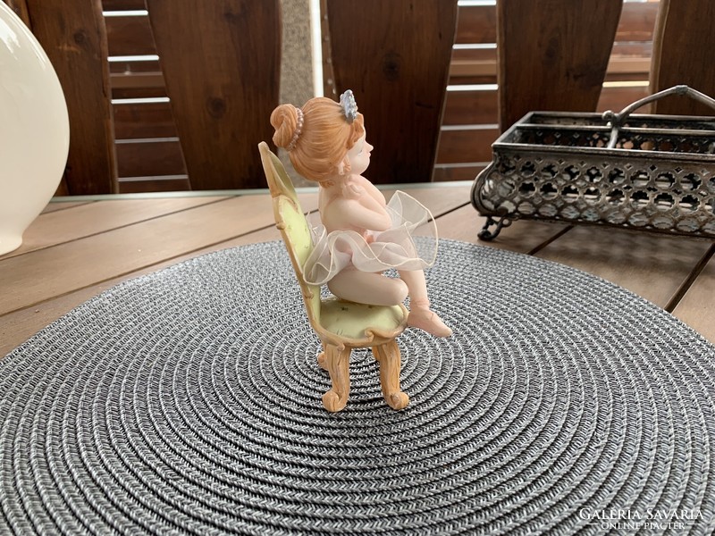 Little ballerina sitting on a vintage chair, Italian