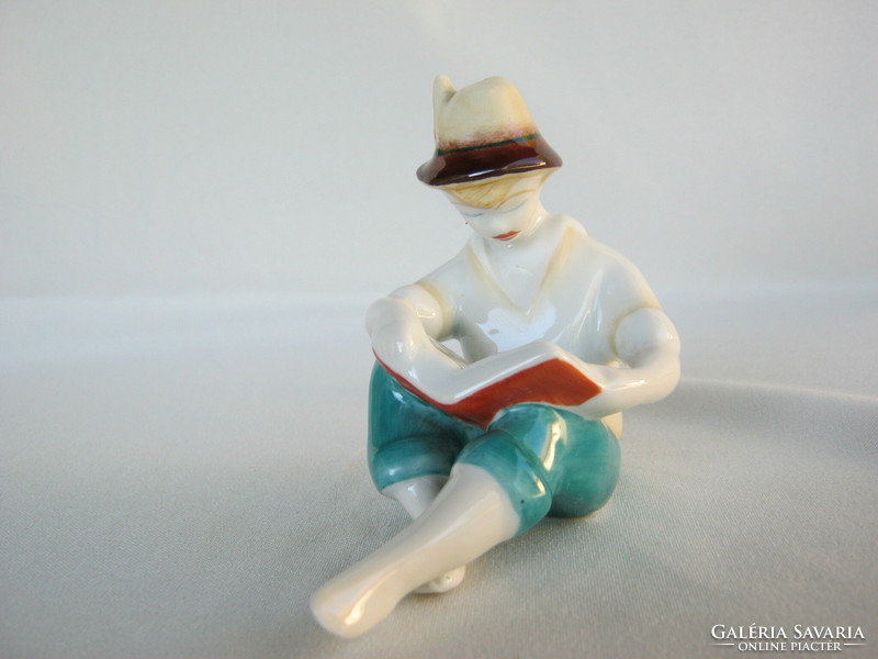 A boy reading a book from Hollóháza porcelain