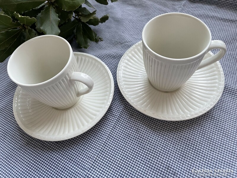 A pair of cream-colored mugs with ribbed walls and clean lines