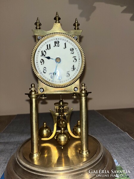 Antique, 400-day rotating pendulum mechanical clock under a glass cover