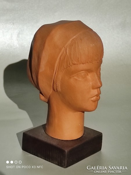 He signaled. A. Terracotta female head bust on wooden pedestal 13 cm