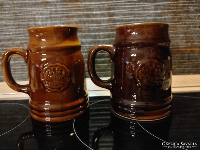 Two ceramic beer mugs, one with a green leaf frog