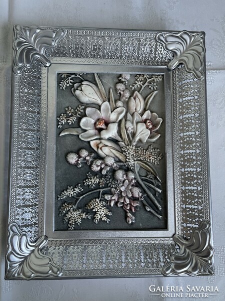 A picture made with beautiful plastic flowers in an openwork metal frame.