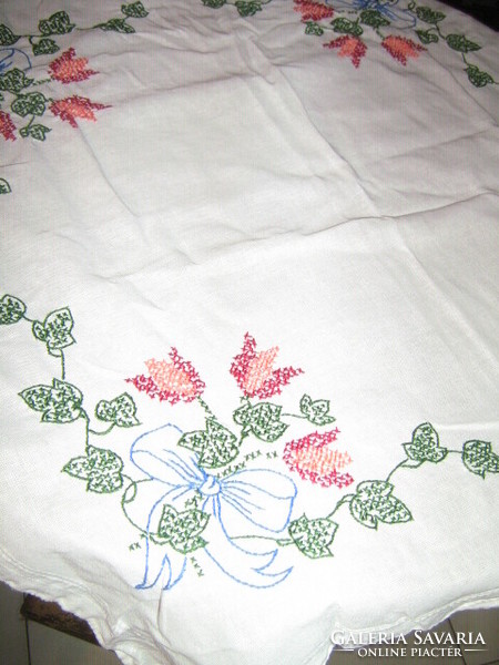 Beautiful hand embroidered bouquet of flowers with cross stitch on white needlework tablecloth