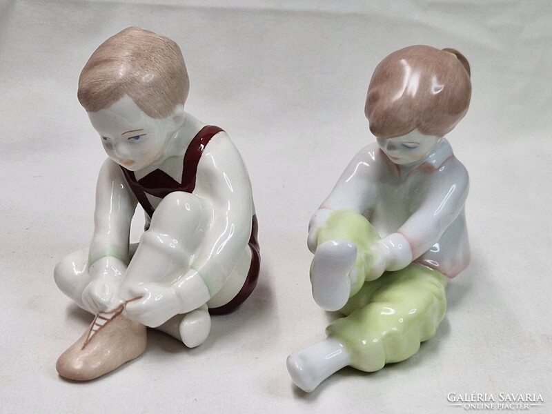 Aquincumi cipőt kötöző fiú és zoknit húzó lány porcelán figurák együtt hibátlan állapotban eladók